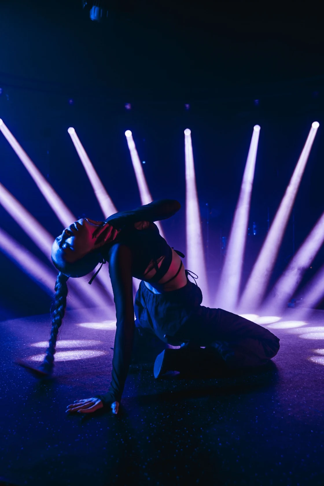 Dancer performing in dramatic blue and violet stage spotlights